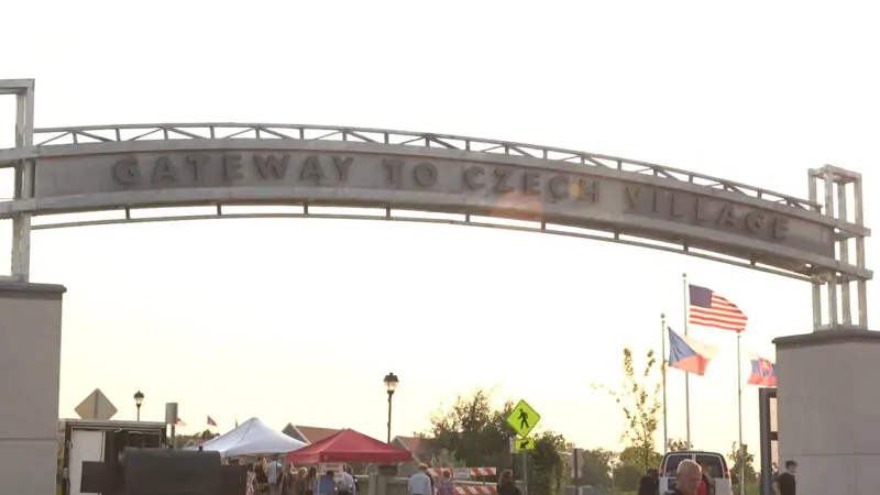Archway sign reading 'Gateway to Czech Village' with flags and tents below