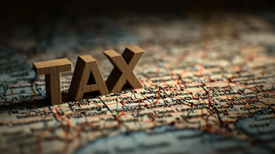 Wooden letters spelling โTAXโ placed on a detailed map, highlighting geographic and property tax concepts