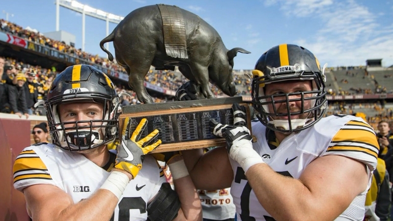 Iowa football players hold up the Floyd of Rosedale trophy after a win over Minnesota