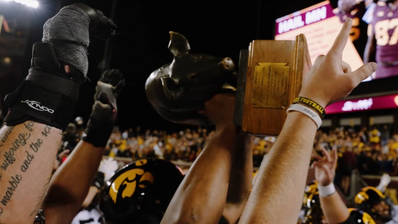 Iowa players raise the Floyd of Rosedale trophy in celebration after a victory