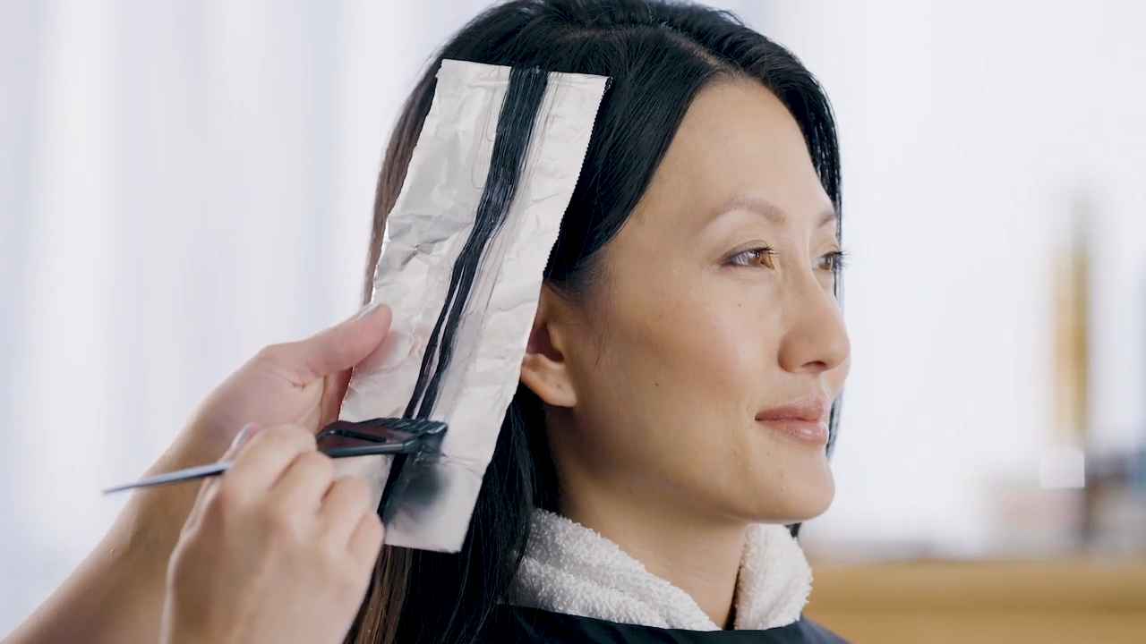 Stylist applying hair color to a woman's hair using foil