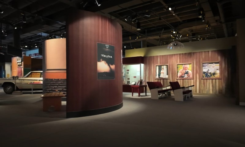 Exhibit room with movie posters, wooden walls, and red theater seats