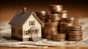 Small house model next to stacked coins placed on paper currency