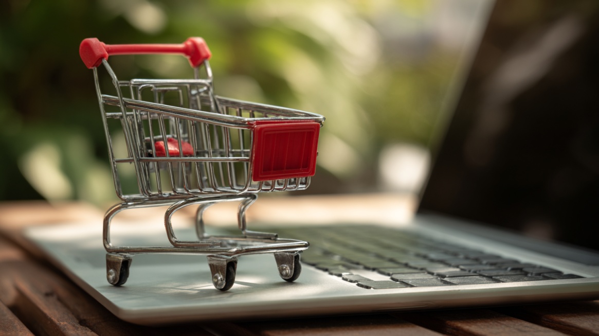 Miniature shopping cart placed on a laptop keyboard, representing ecommerce and online shopping activity