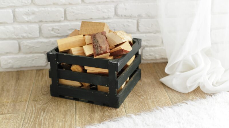 Firewood stored in a crate beside an indoor wall