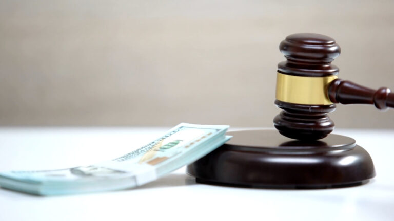 Judge’s gavel beside a stack of cash on a desk
