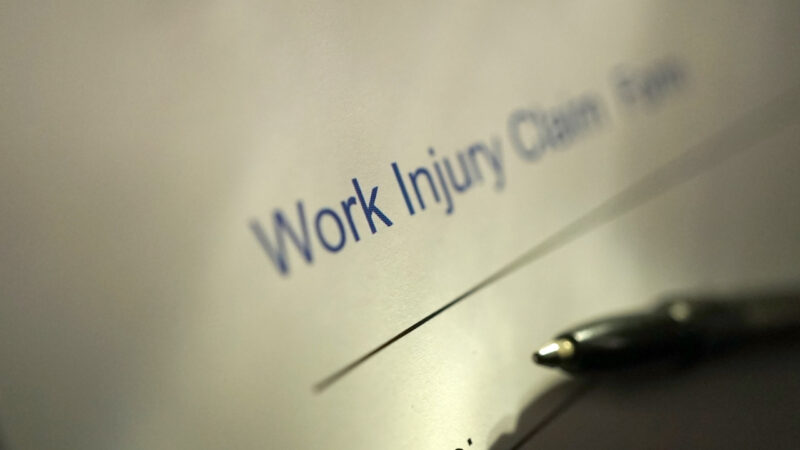 Work injury claim form beside a pen